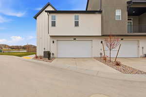 View of front of house featuring driveway, a garage, stucco siding, and a balcony