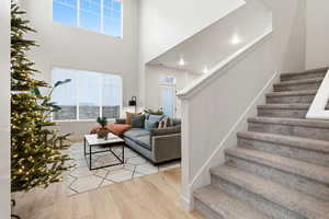 Living room featuring light wood-style floors, stairs, and a towering ceiling