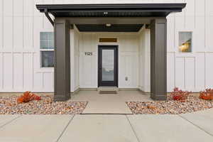 Doorway to property with board and batten siding and a porch