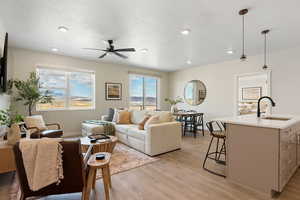 Living room featuring a textured ceiling, a ceiling fan, light wood finished floors, and recessed lighting