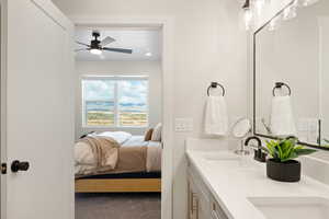 Ensuite bathroom with carpet, double vanity, and a ceiling fan