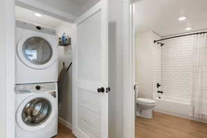 Washroom with recessed lighting, light wood-style flooring, and estacked washer and dryer
