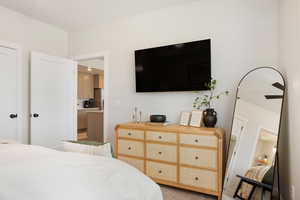 Bedroom featuring ensuite bathroom, light carpet, and freestanding refrigerator