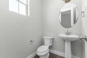 Half bathroom featuring toilet and dark wood-style flooring