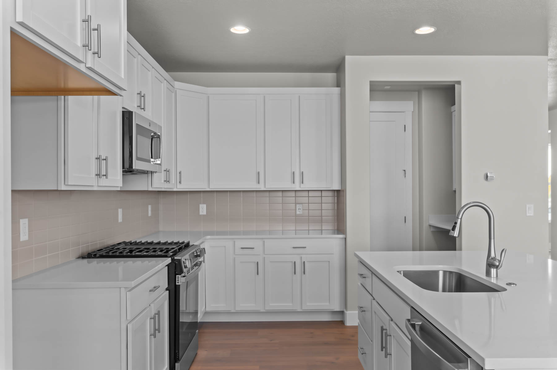 Kitchen featuring stainless steel appliances, dark wood-style floors, white cabinetry, recessed lighting, and light stone countertops