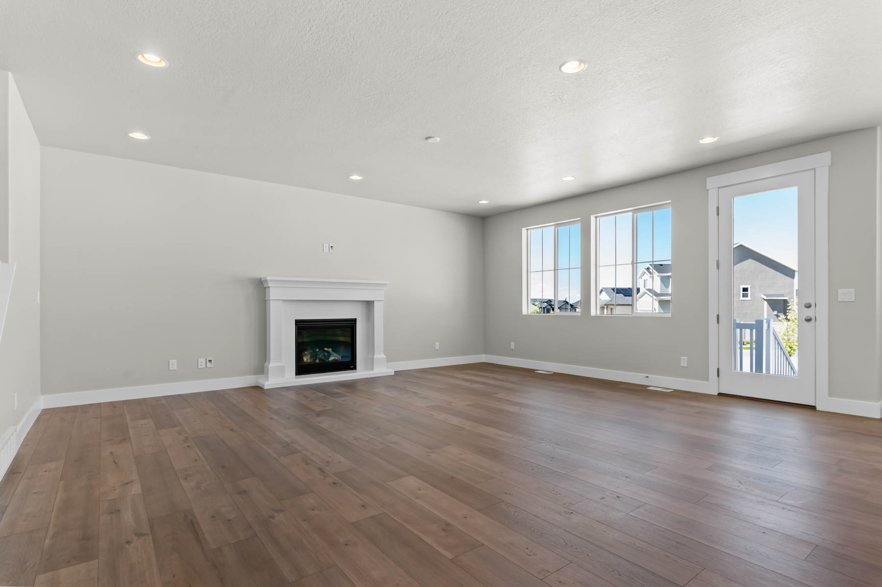 Unfurnished living room featuring a glass covered fireplace, dark wood-type flooring, a textured ceiling, and recessed lighting