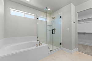 Bathroom featuring a walk in closet, a stall shower, and a garden tub