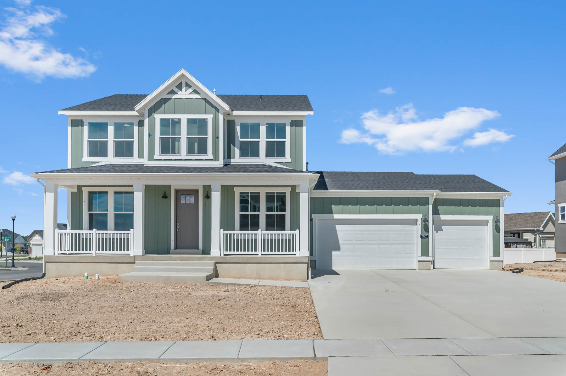 View of front of house with board and batten siding, roof with shingles, a porch, a garage, and concrete driveway