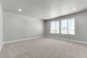 Empty room featuring light carpet, recessed lighting, and a textured ceiling
