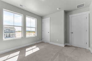 Unfurnished bedroom with light colored carpet and a textured ceiling