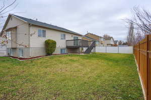 Back of property featuring a deck, stairs, roof with shingles, and a fenced backyard