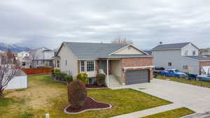 View of front facade with concrete driveway, a shingled roof, a garage, brick siding, and a residential view