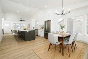 Dining area featuring recessed lighting, light wood-type flooring, a ceiling fan, high vaulted ceiling, and a chandelier