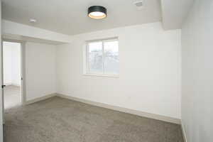 Empty room with light colored carpet and a textured ceiling