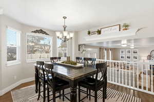 Dining space with dark wood-style floors and a chandelier