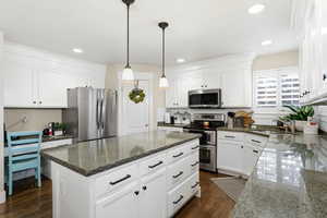 Kitchen with appliances with stainless steel finishes, white cabinetry, hanging light fixtures, dark wood-style floors, and recessed lighting