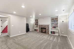 Unfurnished living room with a stone fireplace, light colored carpet, and recessed lighting