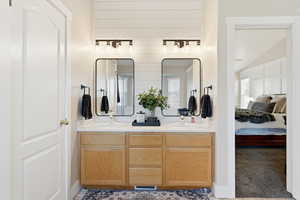 Full bathroom featuring double vanity, ensuite bathroom, and healthy amount of natural light