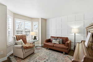 Carpeted living area with a decorative wall and baseboards