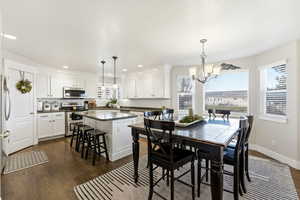 Dining space with dark wood-type flooring, a chandelier, and recessed lighting