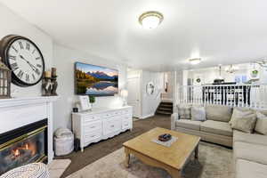 Living room featuring stairs, a fireplace with flush hearth, carpet, and a chandelier