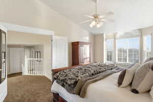 Carpeted bedroom with ceiling fan and high vaulted ceiling