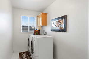 Laundry area featuring cabinet space, washer and clothes dryer, and light tile patterned flooring