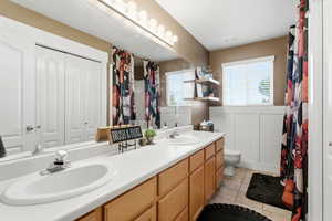 Bathroom featuring double vanity, light tile patterned flooring, a closet, and a shower with curtain