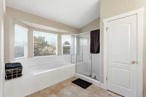 Full bathroom featuring lofted ceiling, a bath, a stall shower, and tile patterned floors