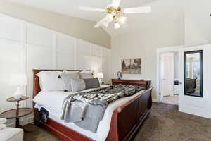 Bedroom featuring lofted ceiling, dark colored carpet, a decorative wall, and ceiling fan