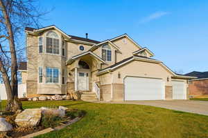 Traditional-style home featuring stucco siding, a front yard, brick siding, and driveway