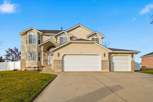 Traditional-style home featuring stucco siding, driveway, brick siding, and an attached garage