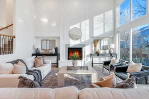 Living room with a high ceiling, a premium fireplace, and wood finished floors
