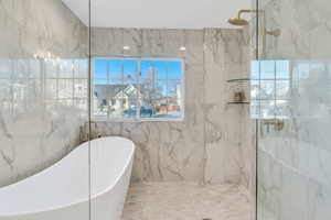 Full bath featuring a freestanding bath and a marble finish shower