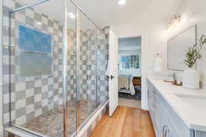 Ensuite bathroom with light wood-type flooring, double vanity, a stall shower, and recessed lighting