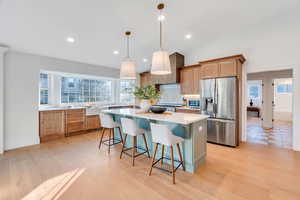 Kitchen featuring stainless steel refrigerator with ice dispenser, a kitchen island, decorative light fixtures, a breakfast bar area, and plenty of natural light