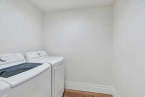 Laundry room featuring wood finished floors and washer and dryer