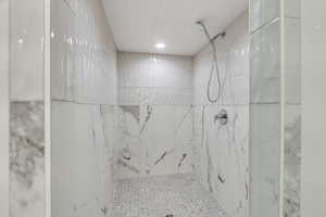 Full bath with a marble finish shower
