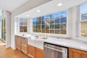 Kitchen featuring stainless steel dishwasher, light stone counters, light wood-style flooring, and recessed lighting