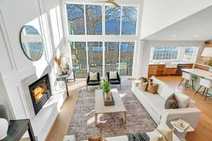 Living area featuring a high end fireplace, light wood finished floors, a towering ceiling, and recessed lighting