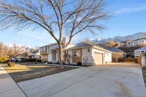 View of front facade with concrete driveway, a garage, a mountain view, a residential view, and stucco siding