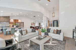 Living area with light wood-style floors, high vaulted ceiling, decorative columns, a ceiling fan, and recessed lighting