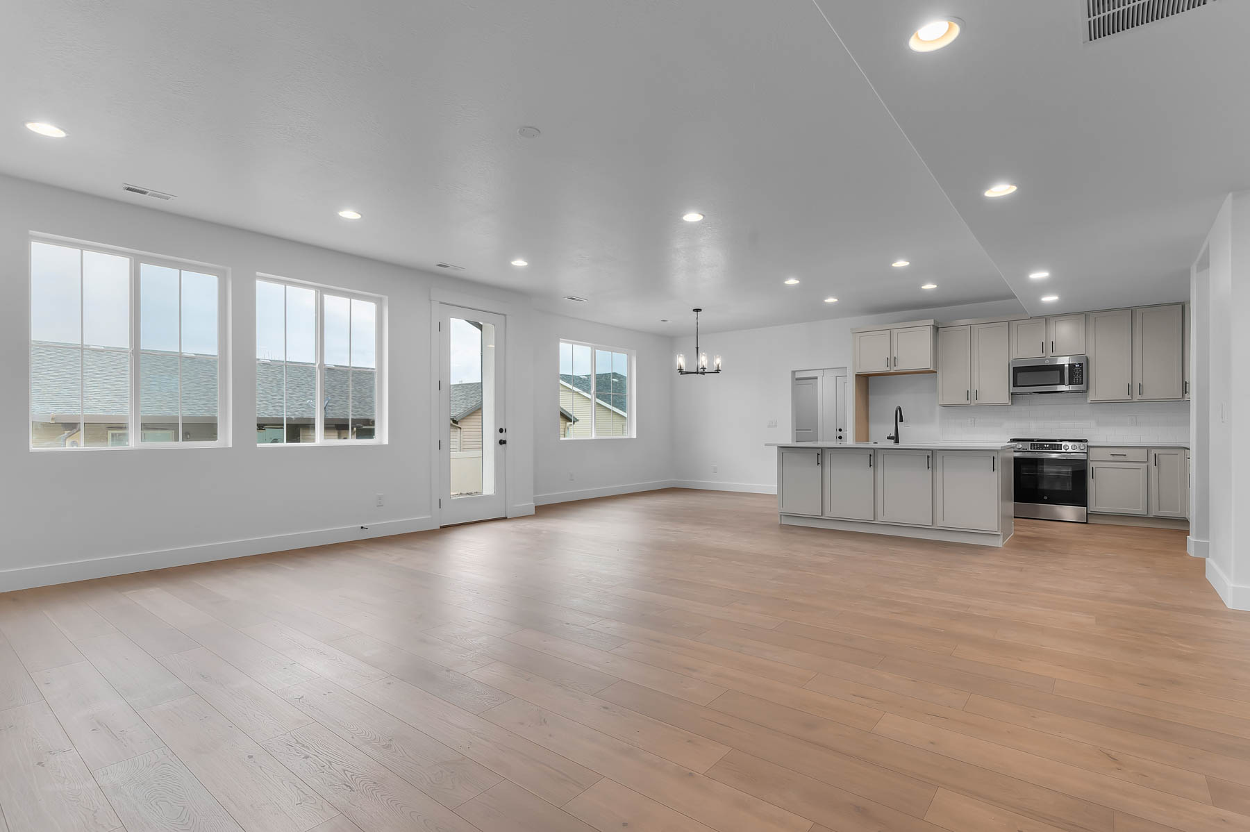 Kitchen with stainless steel appliances, a chandelier, open floor plan, a kitchen island with sink, and light countertops