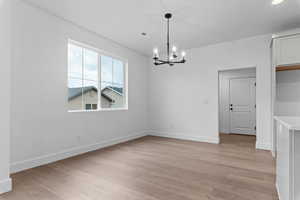 Unfurnished dining area featuring a chandelier and light wood finished floors
