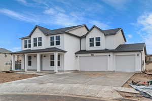 Modern farmhouse style home featuring a garage, concrete driveway, a porch, a shingled roof, and board and batten siding