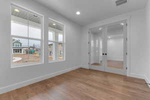 Empty room featuring light wood-style floors, french doors, and healthy amount of natural light