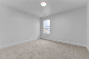 Empty room featuring baseboards and light colored carpet