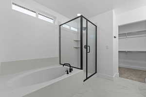 Full bathroom featuring a shower stall, a bath, a spacious closet, and light marble finish floors