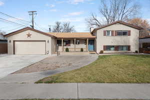 View of front of property with a porch, driveway, a chimney, a garage, and brick siding