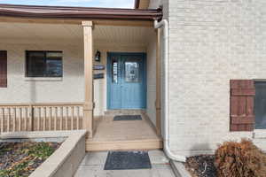 Property entrance featuring brick siding and covered porch